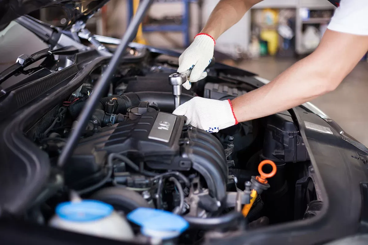 Technicien utilisant une clé à cliquet dans le compartiment moteur d'une voiture