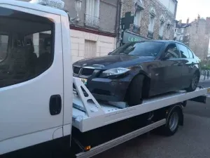 BMW sombre sur plateau de remorquage en milieu urbain parisien