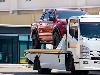 Pickup rouge chargé sur plateau de remorquage